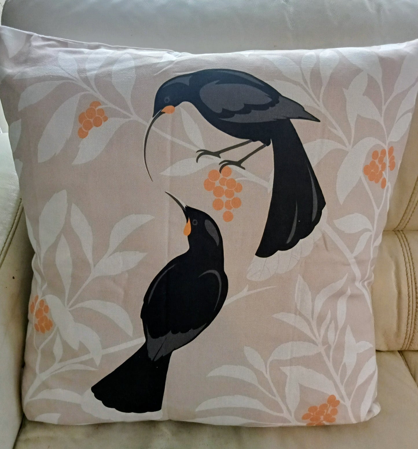 Decorative pillow with huia bird design on a beige background