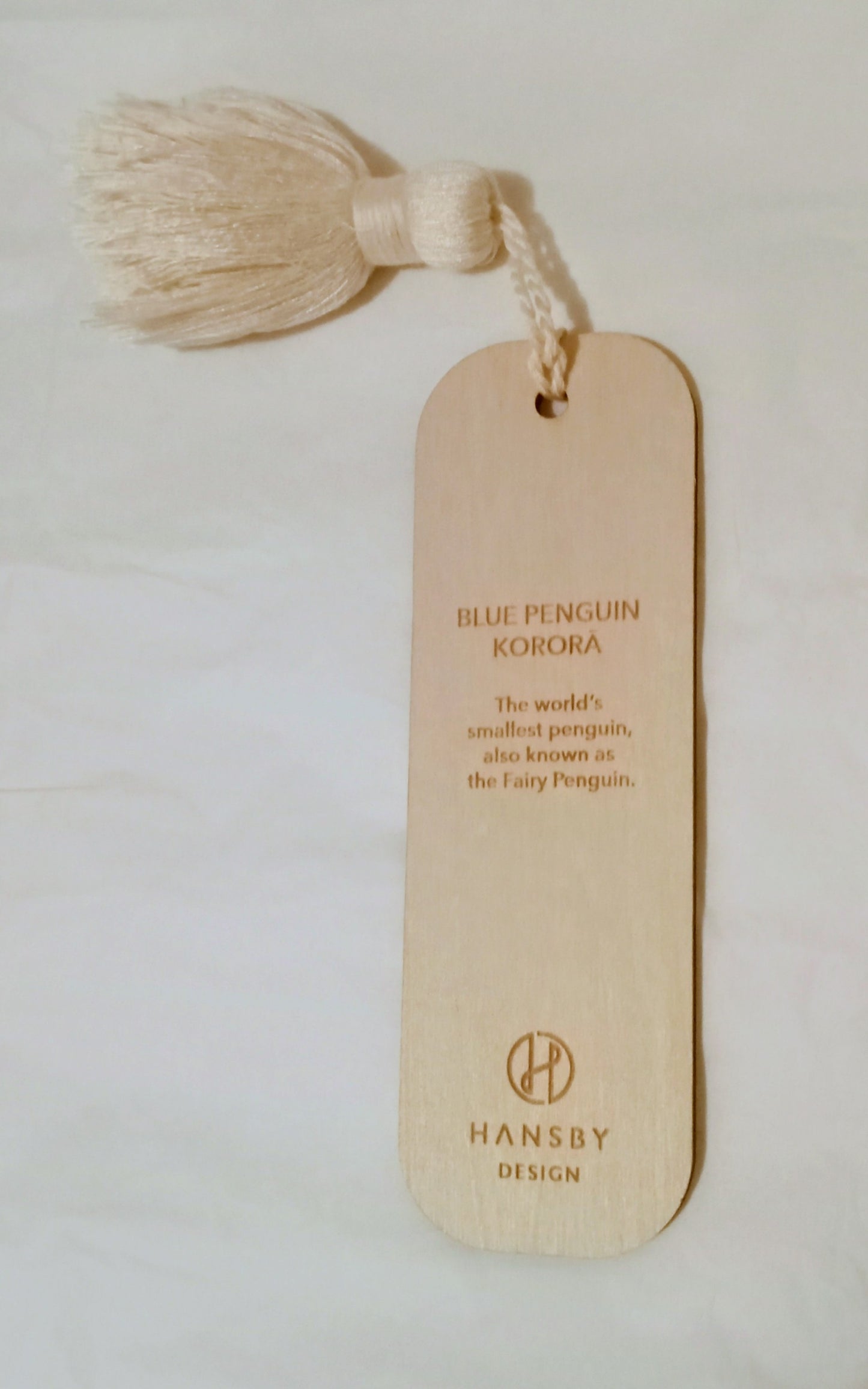 Reverse side of wooden bookmark with tassel and text on a light background