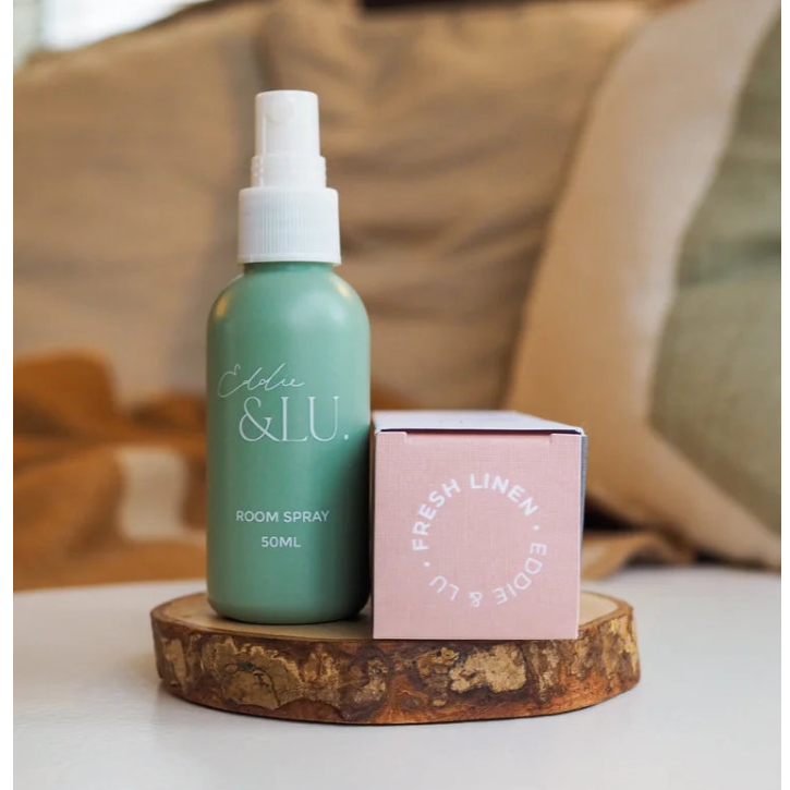 Room spray bottle and packaging on a wooden stand.