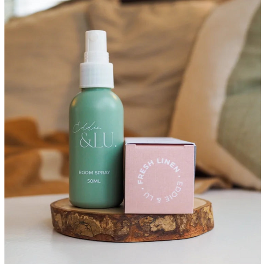 Room spray bottle and packaging on a wooden stand.