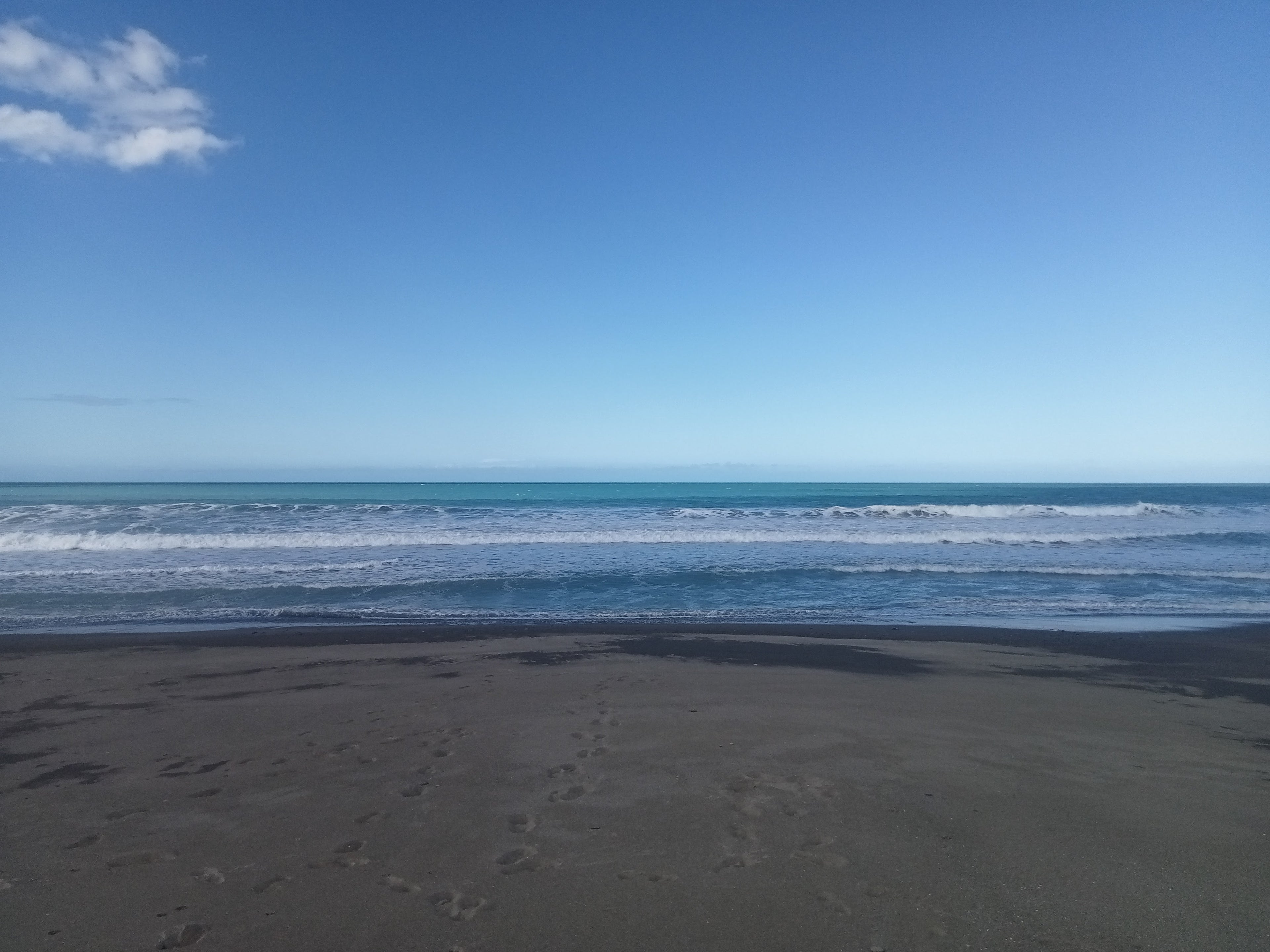 Beach with black sand and blue ocean under a clear sky