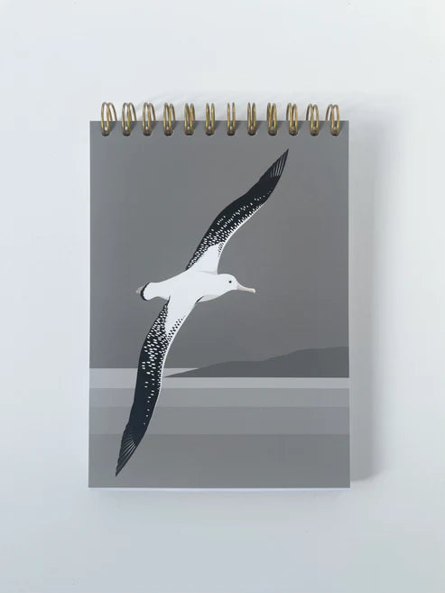 Notebook with an illustration of an Albatross flying over water with headland in background.