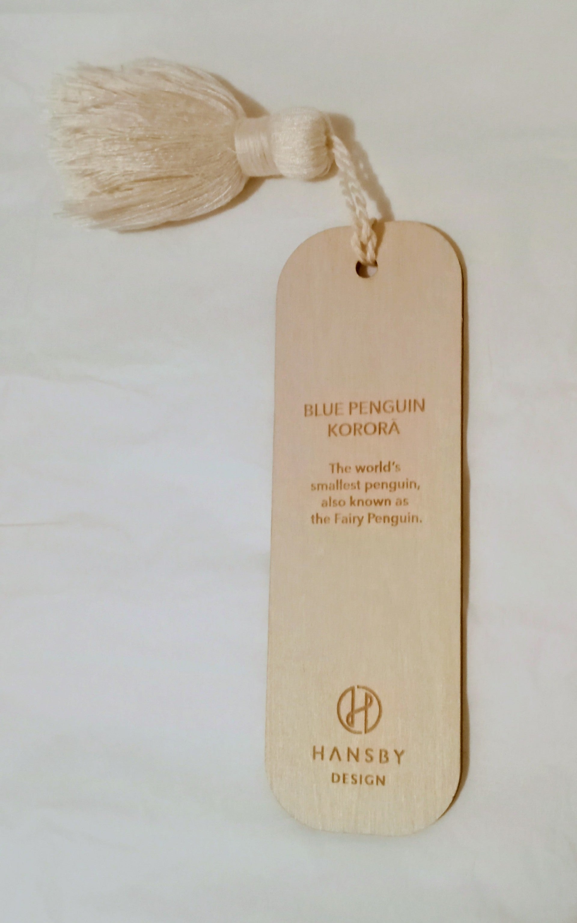 Reverse side of wooden bookmark with tassel and text on a light background
