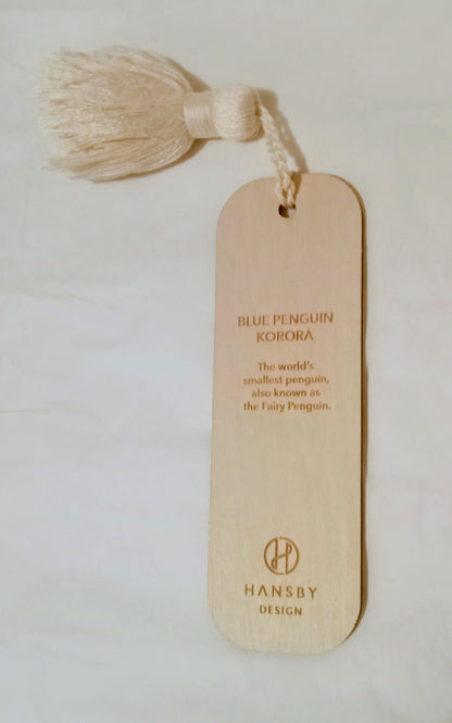 Reverse side of wooden bookmark with tassel and text on a light background