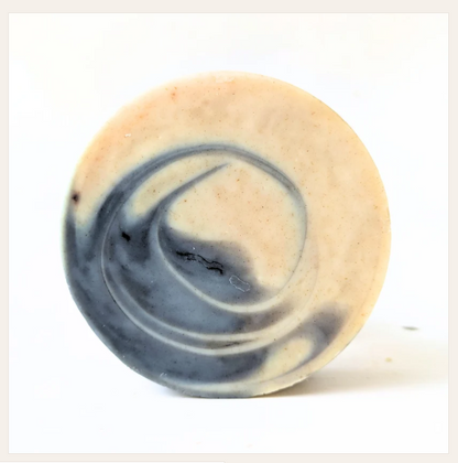 A single round artisan soap bar with a marbled swirl pattern of cream, beige, and slate blue-gray, photographed on a clean white background.