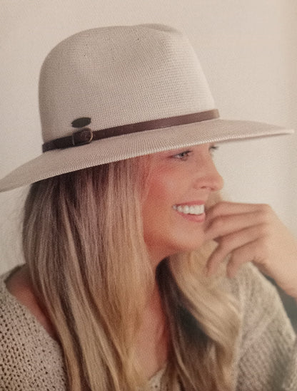 Woman wearing a taupe hat with a narrow brown band against a neutral background