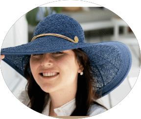 Girl wearing a large-lacey-blue hat against a blurred background