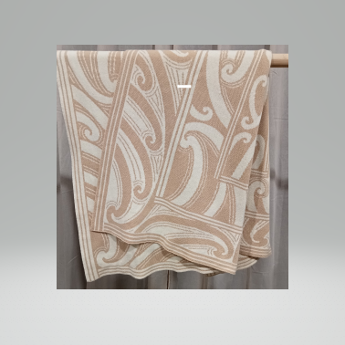 Patterned beige blanket hanging on a rack against a neutral background
